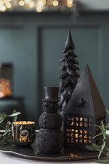 Christmas composition on the green velvet pouf in living room. Beautiful decoration. Christmas trees, candles, stars, lights and elegant accessories. Merry Christmas and Happy Holidays, Template.