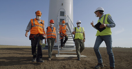 Engineers in masks walking away windmill