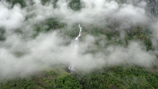 Push-in drone shoot of stunning waterfall in Norway Flam.
Waterfall partly covered by clouds, Nice peaceful scenery.