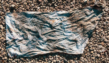 Dirty old wrinkled cloth on gravel
