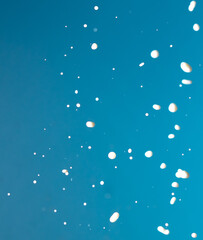 Splashes of white milk isolated on a blue background.