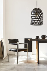 Stylish dining room interior with design wooden family table, black chairs, teapot with mug, mock up art paintings on the wall and elegant accessories in modern home decor. Template.