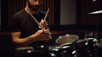 Artist preparing to concert in hall. Musician hitting drumsticks in studio.