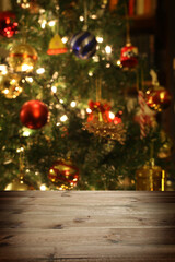 Christmas background: empty wooden table on the foreground and an out of focus Christmas trre on the background