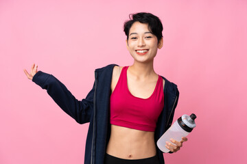 Young sport Asian woman over isolated pink background with sports water bottle