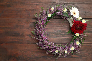 Beautiful autumnal wreath with heather flowers on wooden background, top view. Space for text