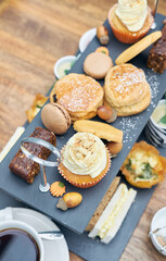 A beautiful gourmet selection of english afternoon tea cakes and scones served with organic cupcakes, tea and coffee, strawberry jam and clotted cream. traditional british food.