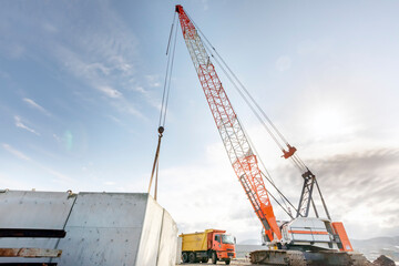 The big crawler crane and other construction machineries are working to build pier of the harbor. A crawler crane has its boom mounted on an undercarriage fitted with a set of crawler tracks.