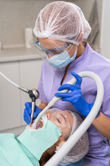 The dentist with the help of specialized tools provides treatment of the oral cavity to the girl patient.