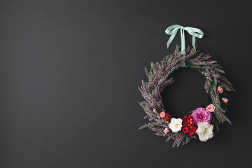 Obraz premium Beautiful autumnal wreath with heather flowers hanging on black background. Space for text