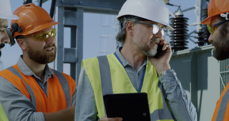 Mature engineer talking on smartphone during meeting on power station
