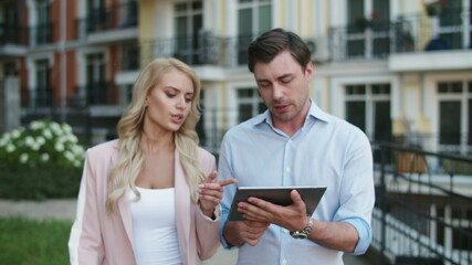 Entrepreneurs using tablet computer at street. Business couple walking together