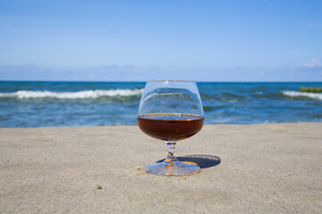 Cognac in a glass on the shore of the blue sea. Stay with alcohol