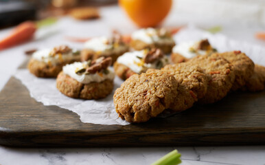 Keto Carrot oatmeal cookies. Healthy homemade ketogenic diet dessert decorated with white cream, nut and seeds. set on white cafe table background.