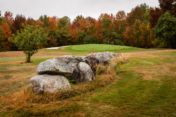 Granite rocks anchor the fairway on a golf course with fall leaf colors in bloom near Dedham, Maine