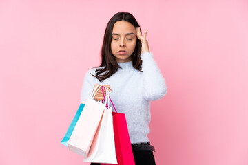 Young woman with shopping bag over isolated pink background with headache