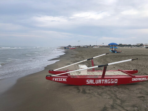 Red Italian lifeguard rescue boat with oars at a beach in Fregene, next to Rome. 