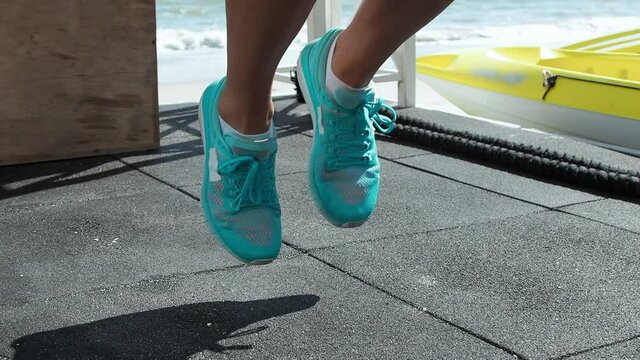 Blond woman trains legs. Running on the spot Crossfit with a trainer. On the beach. Close-up