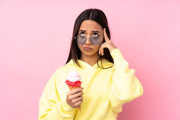 Young brunette girl holding a cornet ice cream over isolated pink background thinking an idea