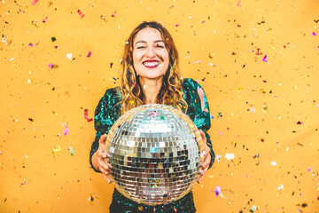Happy fashion girl holding disco ball with confetti around the scene - Party, event and celebration...