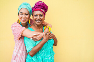 Happy mother and daughter with traditional african dresses smiling on camera - Focus on faces