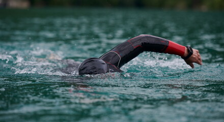 triathlon athlete swimming on lake wearing wetsuit