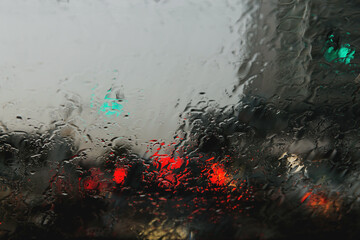 City road seen through rain drops on the car windshield.