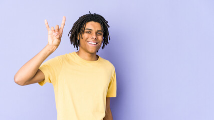 Young african american rasta man showing a horns gesture as a revolution concept.