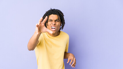 Young african american rasta man showing claws imitating a cat, aggressive gesture.