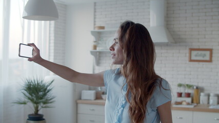 Beautiful woman taking selfie photo in kitchen. Woman posing for photo.
