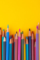 Many colorful pencils on yellow background