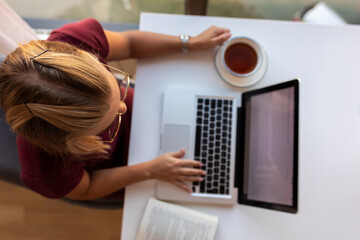 Woman using a laptop and drinking beverage