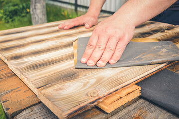 sanding a wooden surface/man's hand processes a wooden surface with sandpaper