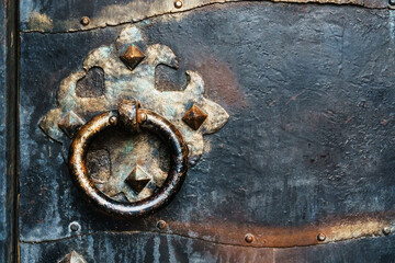 Steel black door of an ancient castle with a round vintage handle.