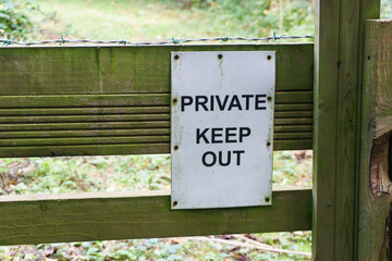 Obraz premium Private keep out sign on a gate with barbed wire on a forest trail