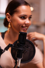Smiling young woman making podcast recording for online show in home studio. Creative online show On-air production internet broadcast host streaming live content, recording digital social media