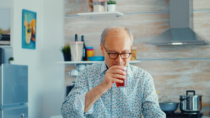 Fototapeta premium Authentic senior man on online video call in the morning in cozy kitchen. Elderly person using internet online chat technology video webcam making a video call connection camera communication