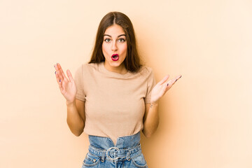 Young caucasian woman isolated en beige background surprised and shocked.