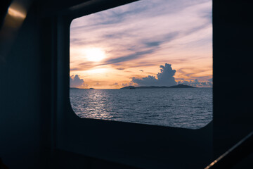 View from the window of the ferry boat to the colorful sunrise over the sea and islands. Sea travel and adventures. 