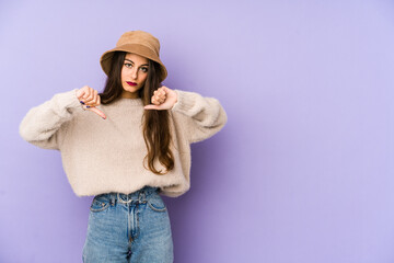 Young caucasian woman isolated on purple background showing a dislike gesture, thumbs down. Disagreement concept.