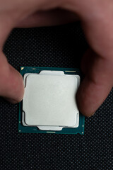 Fingers holding cpu microchip on black background. Micro photography, top view.