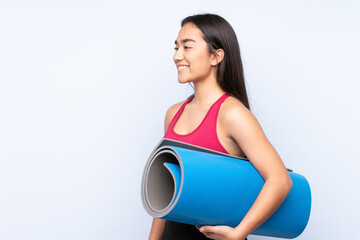 Young Indian sport woman isolated on blue background with a mat