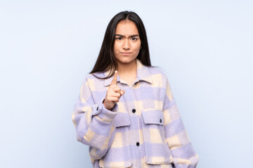 Young Indian woman isolated on blue background frustrated and pointing to the front