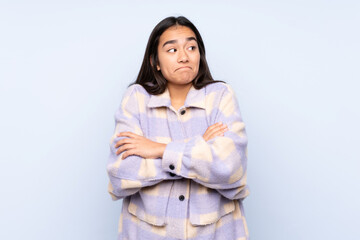 Fototapeta premium Young Indian woman isolated on blue background making doubts gesture while lifting the shoulders