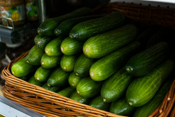 Long green cucumbers in a basket on a store counter.