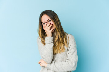 Young caucasian woman isolated on blue background laughing happy, carefree, natural emotion.