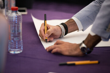 Detail view of a person holding a pen in a conference