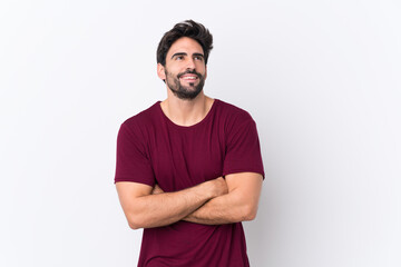 Fototapeta premium Young handsome man with beard over isolated white background looking up while smiling