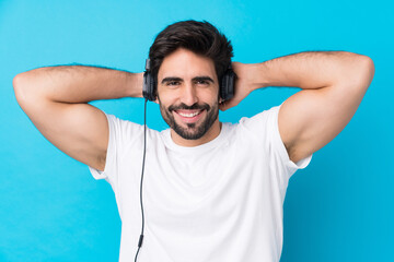 Fototapeta na wymiar Young handsome man with beard over isolated blue background listening music