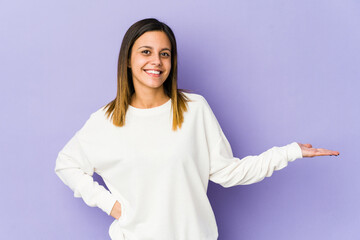 Young woman isolated on purple background showing a welcome expression.
